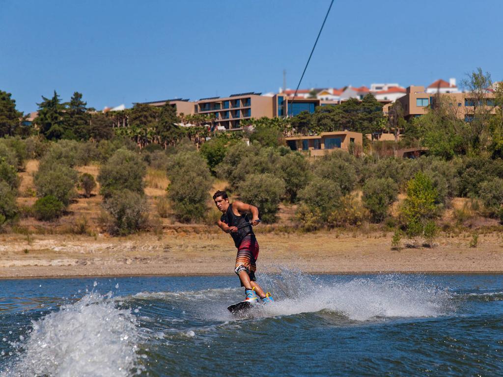 Ap Lago Montargil - Conference & Spa Екстер'єр фото The photo shows a person wakeboarding on a body of water. The individual is being pulled by a cable, which is likely connected to a boat or a winch. The person is wearing a life jacket and swim shorts, balancing on the board as they enjoy the activit