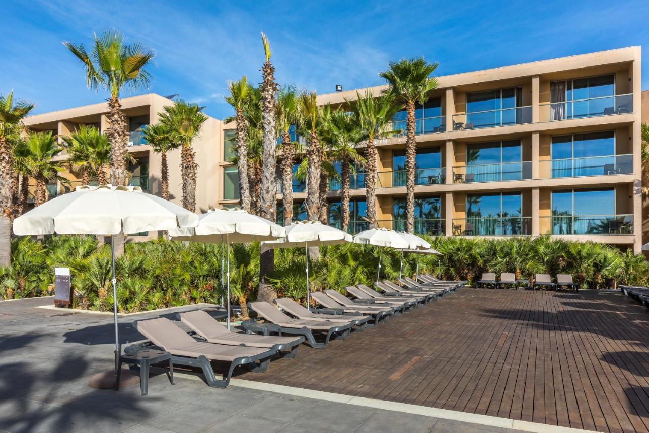 Ap Lago Montargil - Conference & Spa Екстер'єр фото The photo shows a modern resort or hotel area featuring several lounge chairs lined up on a wooden deck. Each lounge chair is paired with a white umbrella, providing shade. In the background, there are palm trees, which add to the tropical atmosphere