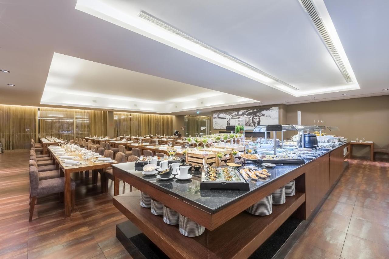 Ap Lago Montargil - Conference & Spa Екстер'єр фото The photo displays a spacious restaurant interior, featuring a well-organized dining area with multiple tables set for patrons. In the center, there is a large buffet station filled with an array of food items. The decor is modern and elegant, with w
