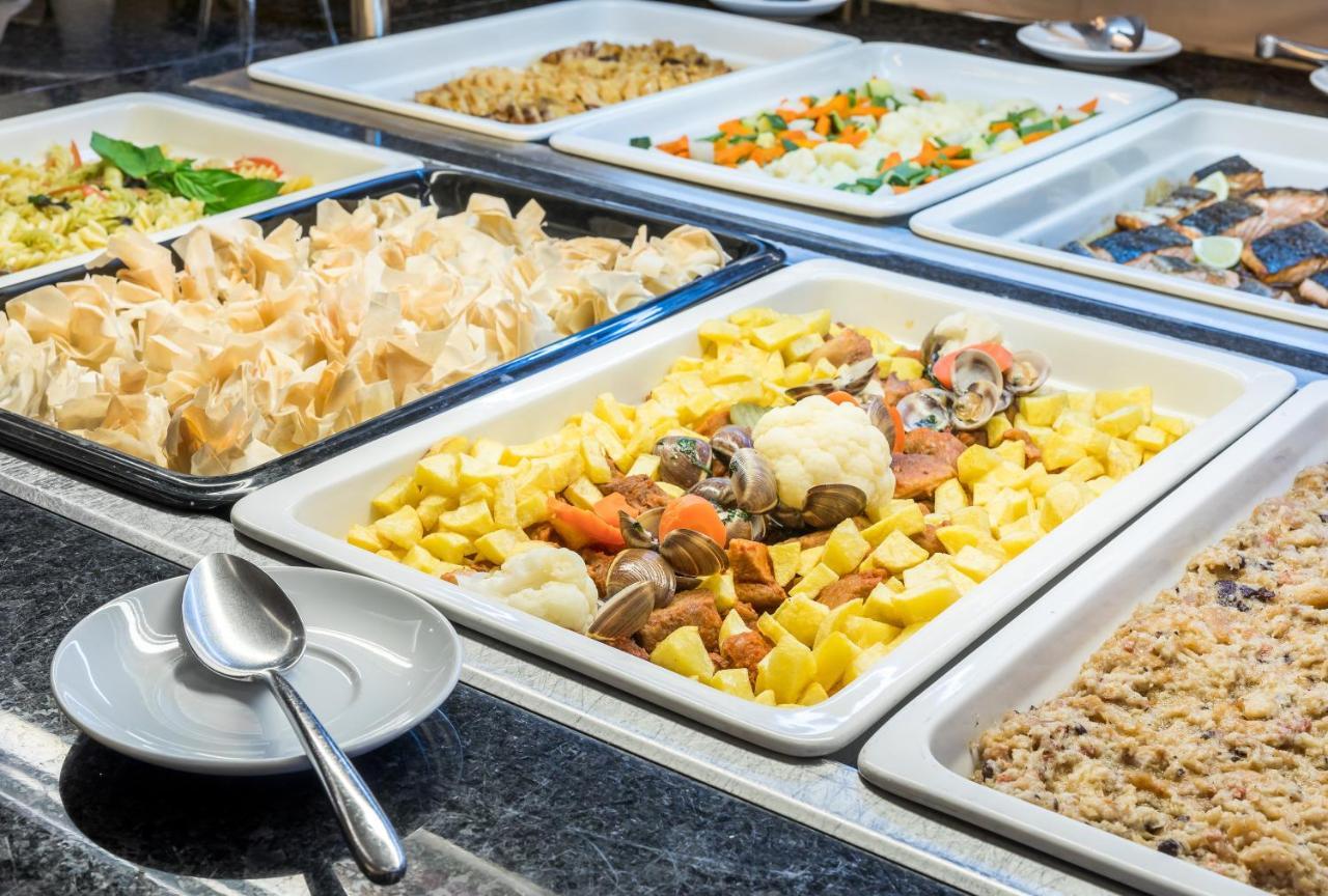 Ap Lago Montargil - Conference & Spa Екстер'єр фото The photo shows a buffet-style display of various dishes. There are several rectangular trays filled with different types of food. 

1. One tray contains a mix of vegetables and seafood, likely including potatoes and cauliflower.
2. Another tray hold