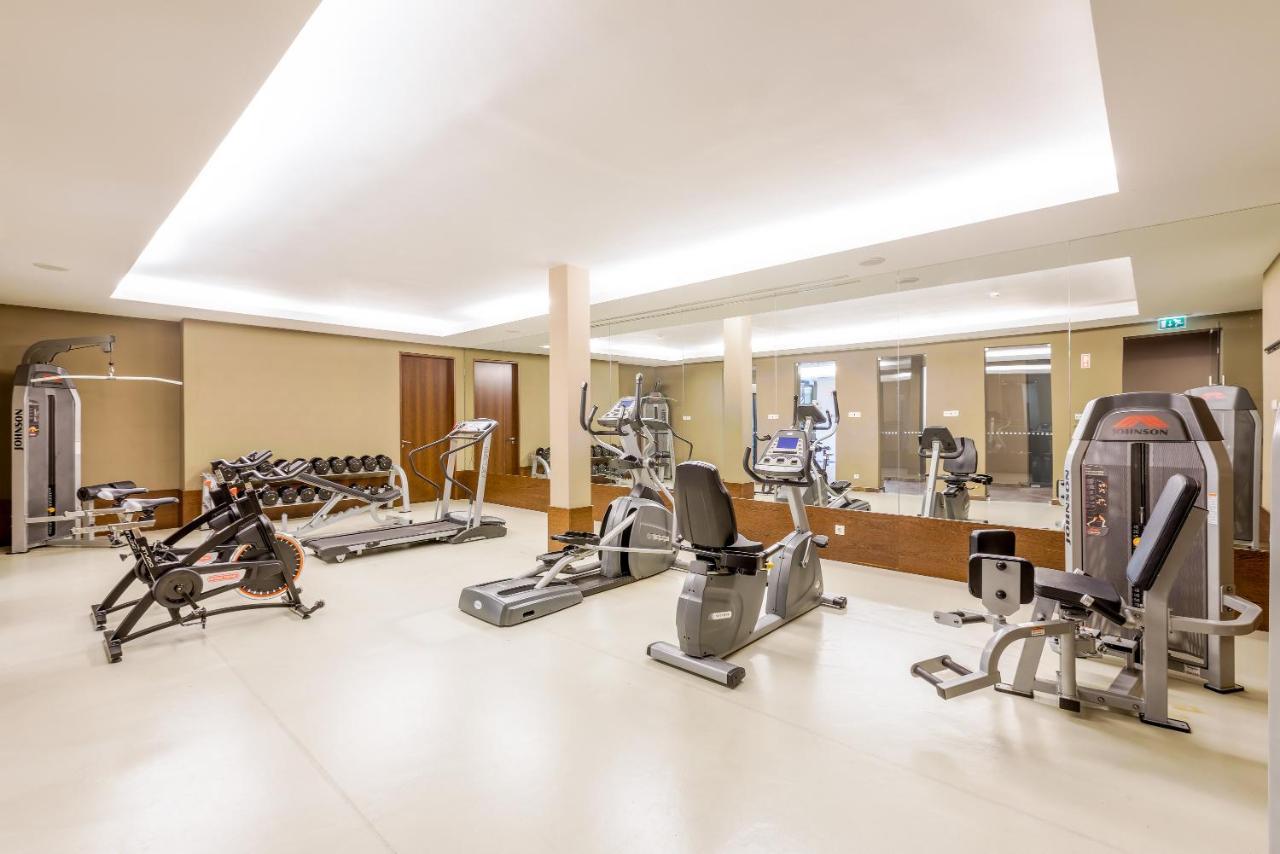 Ap Lago Montargil - Conference & Spa Екстер'єр фото The image shows a modern gym interior featuring various exercise equipment. On the left, there are free weights and weight benches. In the center, there are multiple machines, including a stationary bike and an elliptical. The space is well-lit with 