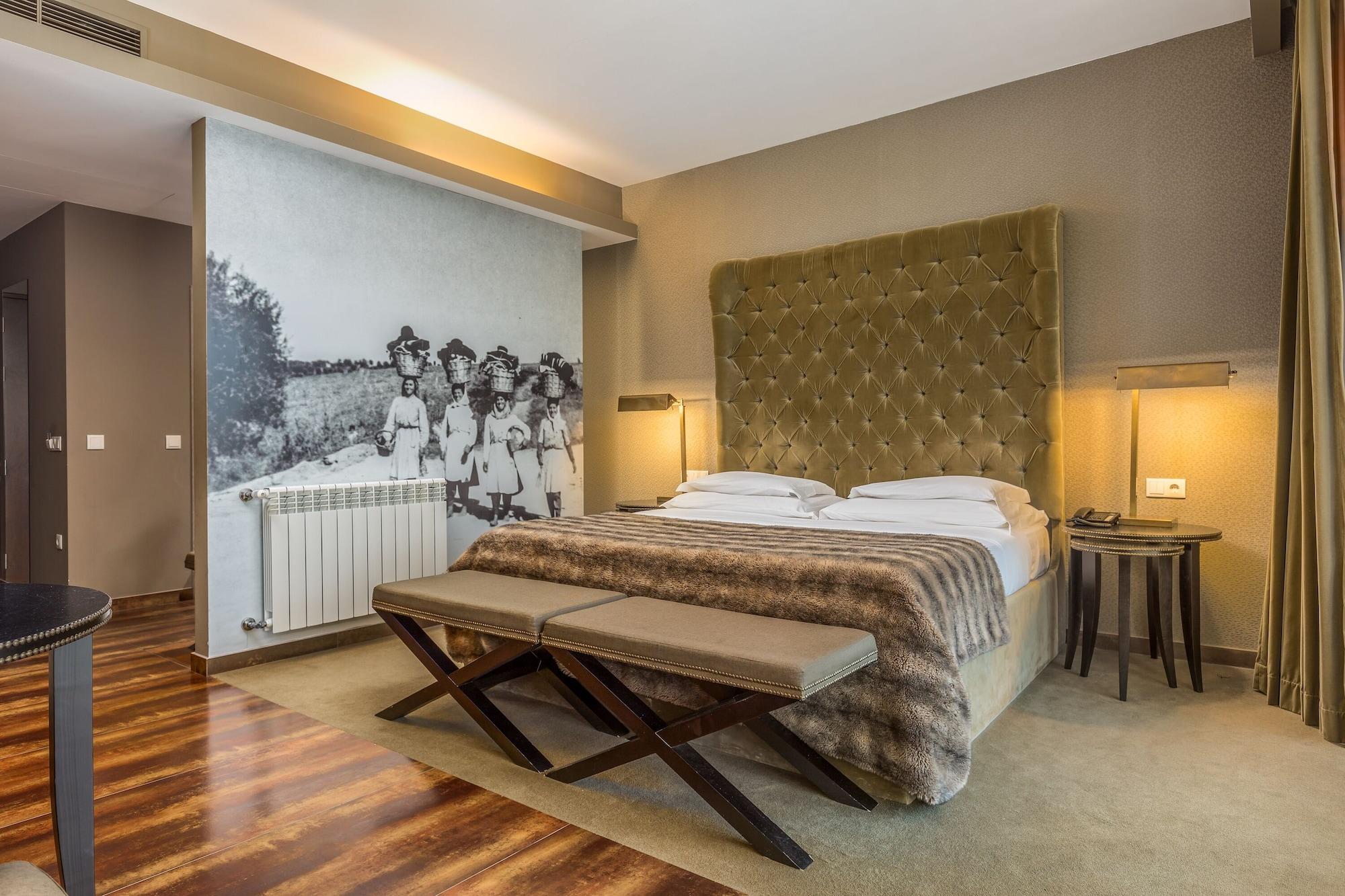 Ap Lago Montargil - Conference & Spa Екстер'єр фото The photo shows a modern hotel room with a large, plush bed that has a tufted, green headboard. The bedding is white with a textured blanket at the foot of the bed. A decorative wall behind the bed features a black and white mural of children in a fi