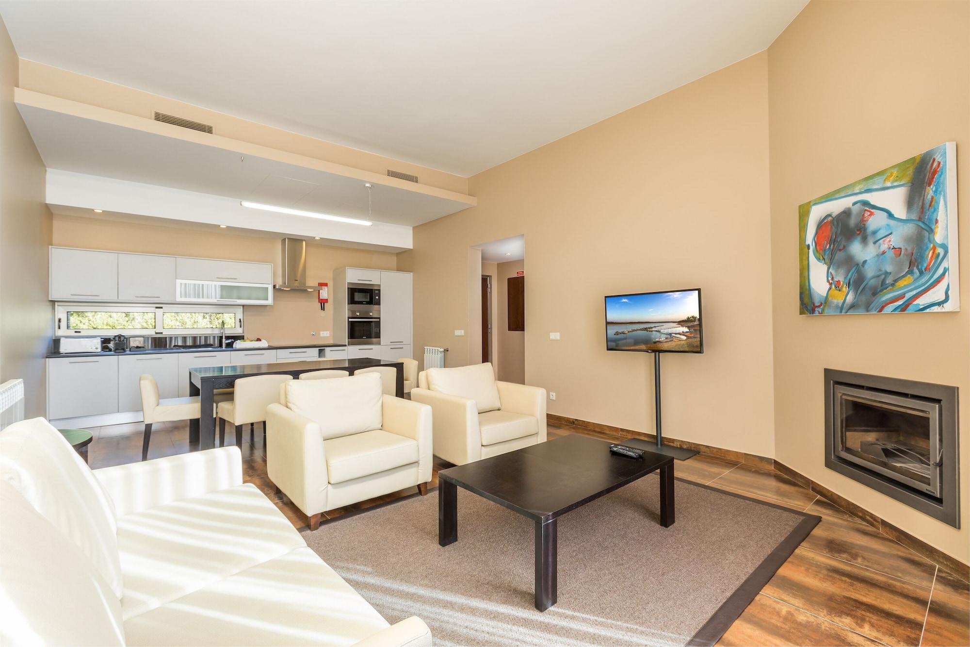 Ap Lago Montargil - Conference & Spa Екстер'єр фото The photo shows a modern, spacious living area with a contemporary design. The room features light-colored walls and wooden flooring. 

In the center, there is a black coffee table surrounded by four white armchairs. A flat-screen TV is mounted on th