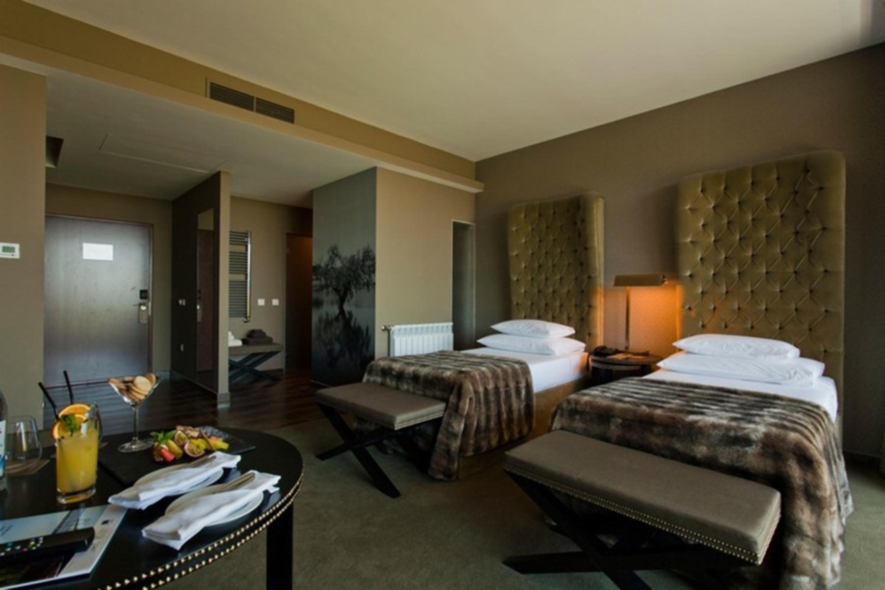 Ap Lago Montargil - Conference & Spa Екстер'єр фото The photo shows a stylish hotel room featuring two beds with plush, upholstered headboards. The room has a modern and elegant design, with earthy tones dominating the decor. A small round table is set up in the foreground, displaying a drink and some